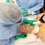 a nursing student intubating a male nursing mannikin