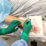 a student inserting an IV into a nursing mannikin