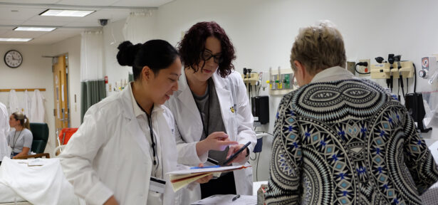 two women in white lab coats discussing something together