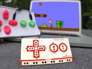 A homemade video game controller in front of a tv with Super mario on it